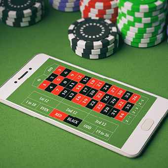Casino chips and smartphone on green felt.