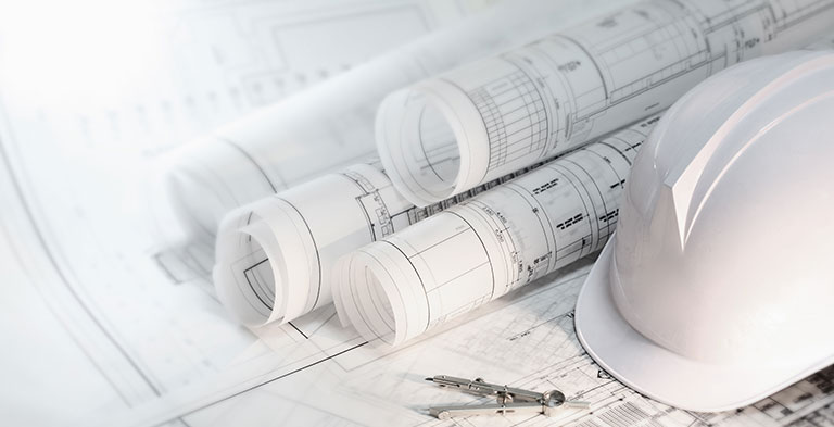 Hard hat and compass on architectural blueprints