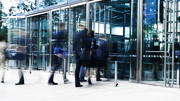 Businesspeople Entering Through Glass Doors of Office Building, Blurred Motion